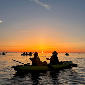 Two people sitting in a kayak watching the sunrise in Malta on calm water.