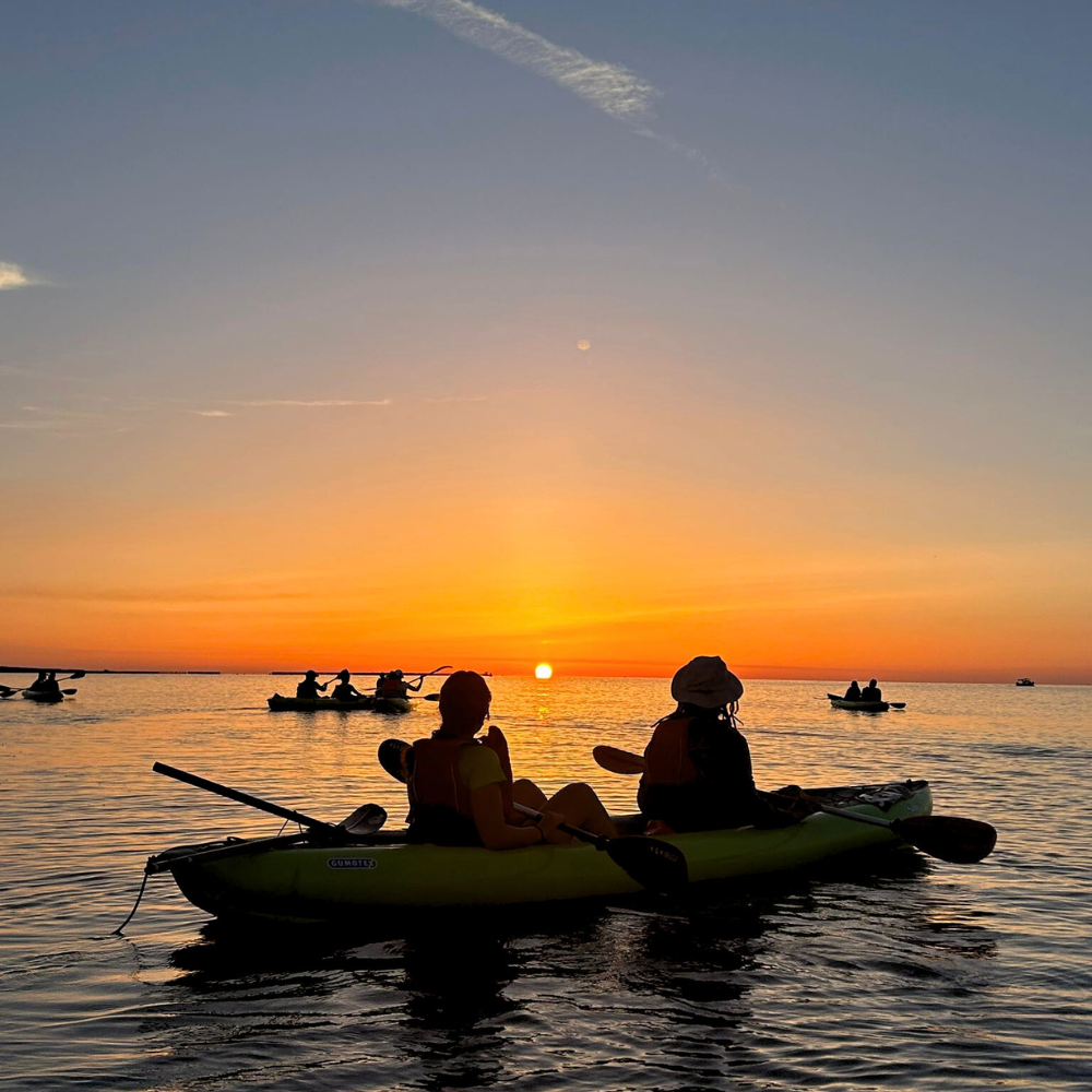 Two people sitting in a kayak watching the sunrise in Malta on calm water.