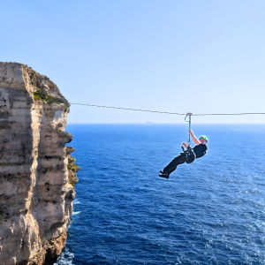 Man riding the zipline in Malta, suspended above the landscape on the cable.