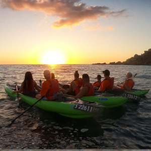 Kayaking group watching the sunset from their kayaks on calm water.