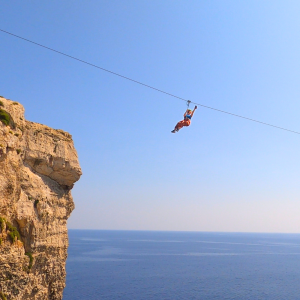 Girl taking a selfie while riding the zipline, secured with harness and trolley.