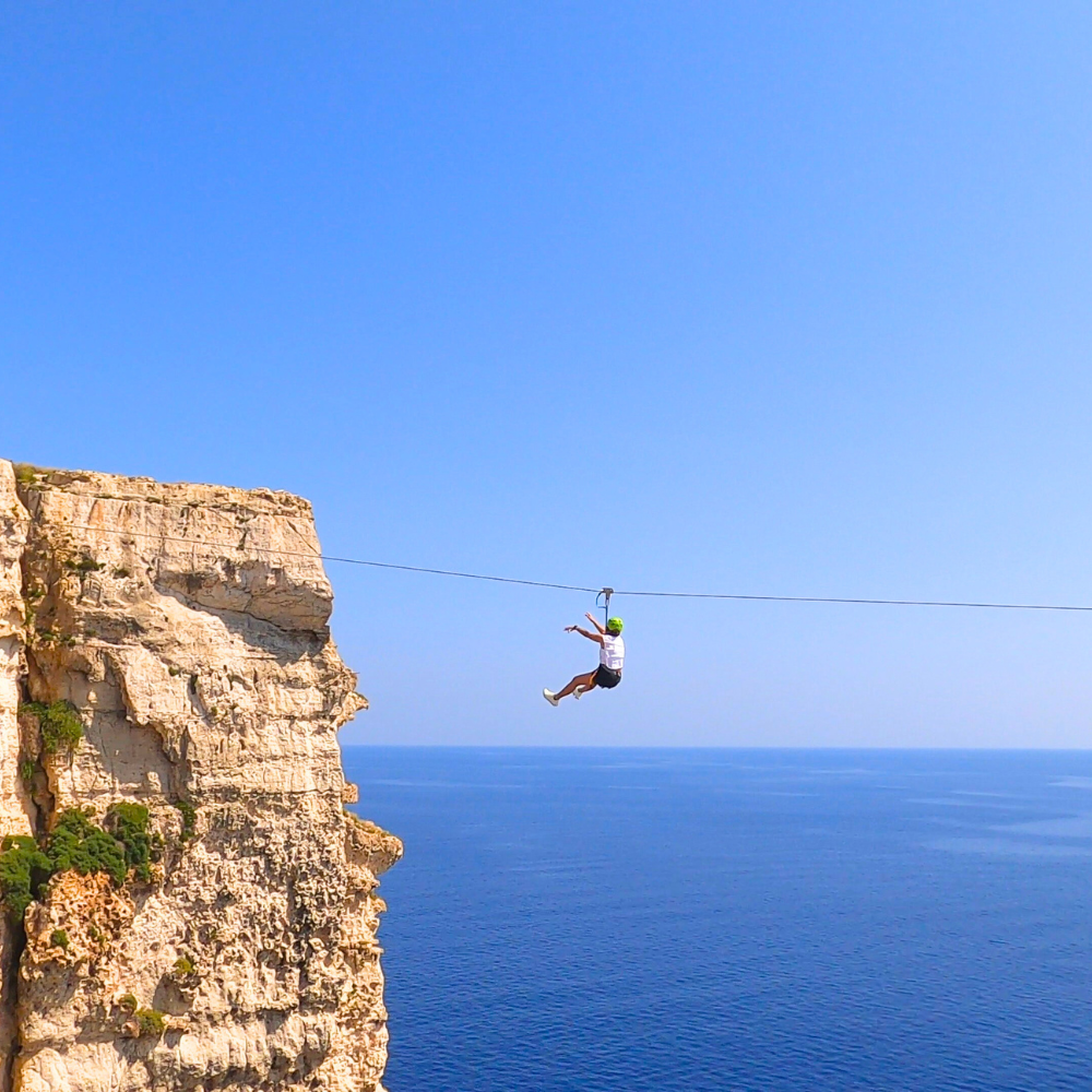 Woman riding the zipline in Malta, secured with harness and trolley.