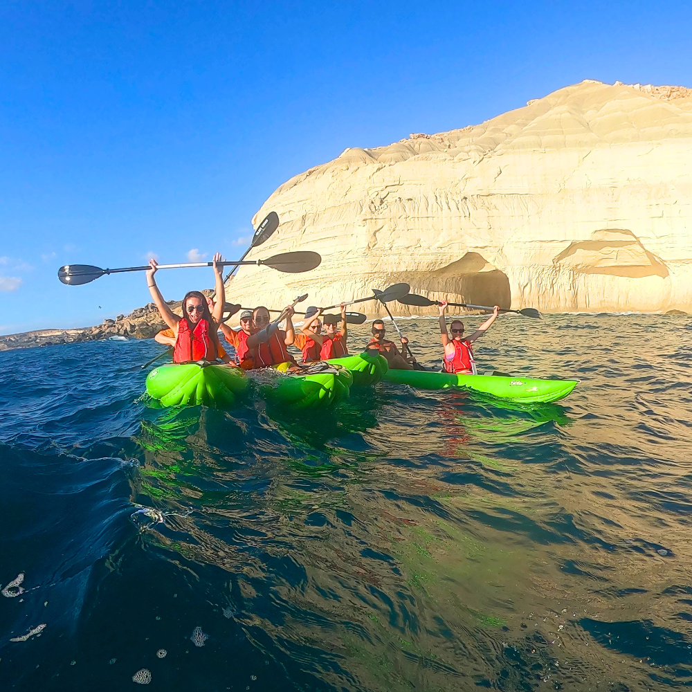 Kayaking group gathered in front of Santa Maria Cave in Malta, sitting in their kayaks on the water.