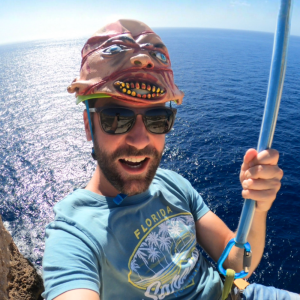 Man riding the zipline at Halloween wearing a scary Halloween mask on his helmet.