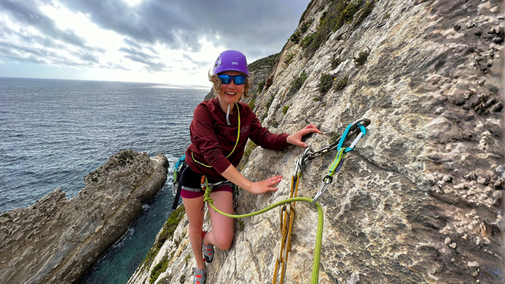 Woman smiling while rock climbing in Xaqqa Valley, Malta